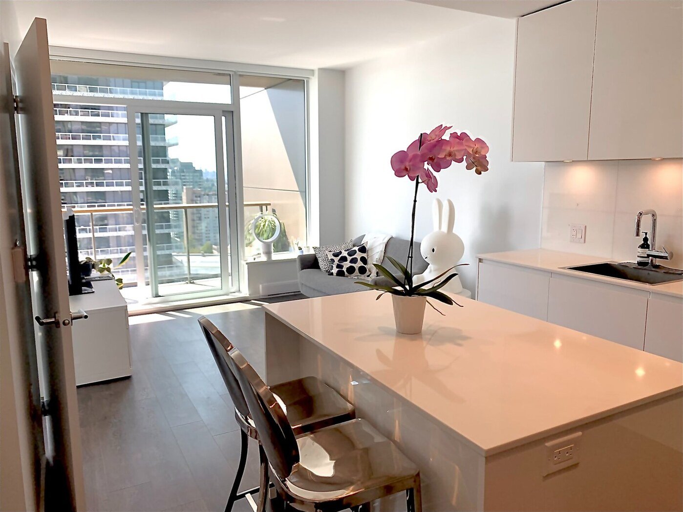 Open concept living room and kitchen at Suite 1806, The Amazing Brentwood — fully furnished with city views