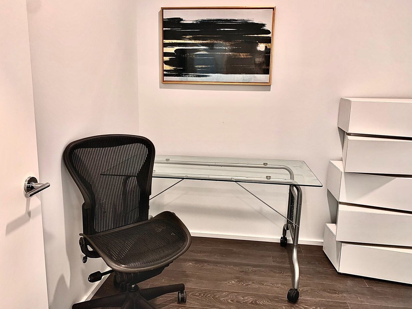 Den office with glass desk and Herman Miller Aeron chair